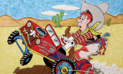 a red-headed cowboy struggles to control a red cart that reads, Git Along Lil’ Doggie. On the verge of tipping over, the cart sputters along on an empty desert landscape.