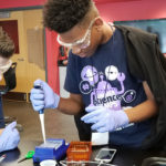 two young boys, wearing goggles, andworking on a science experiment in a high-tech classroom