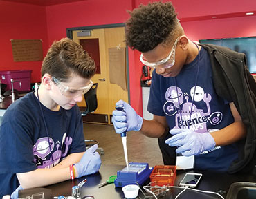 two young boys, wearing goggles, andworking on a science experiment in a high-tech classroom