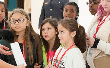An art docent talking to a group of young students in an art gallery.