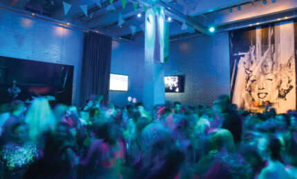 A blurred image of a group of teens dancing in the Andy Warhol Museum lobby.