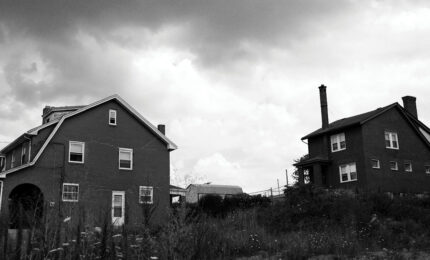 A black and white photo of two abandoned homes