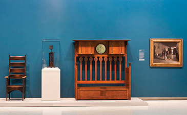 A art gallery image showing artwork against a bright blue colored wall.