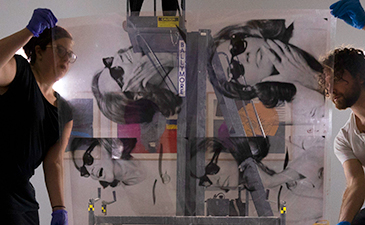 Two art handlers preparing to photograph an acetate used by Andy Warhol to make his prints.
