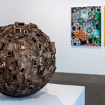 A view of an art gallery with a wooden sphere in the foreground