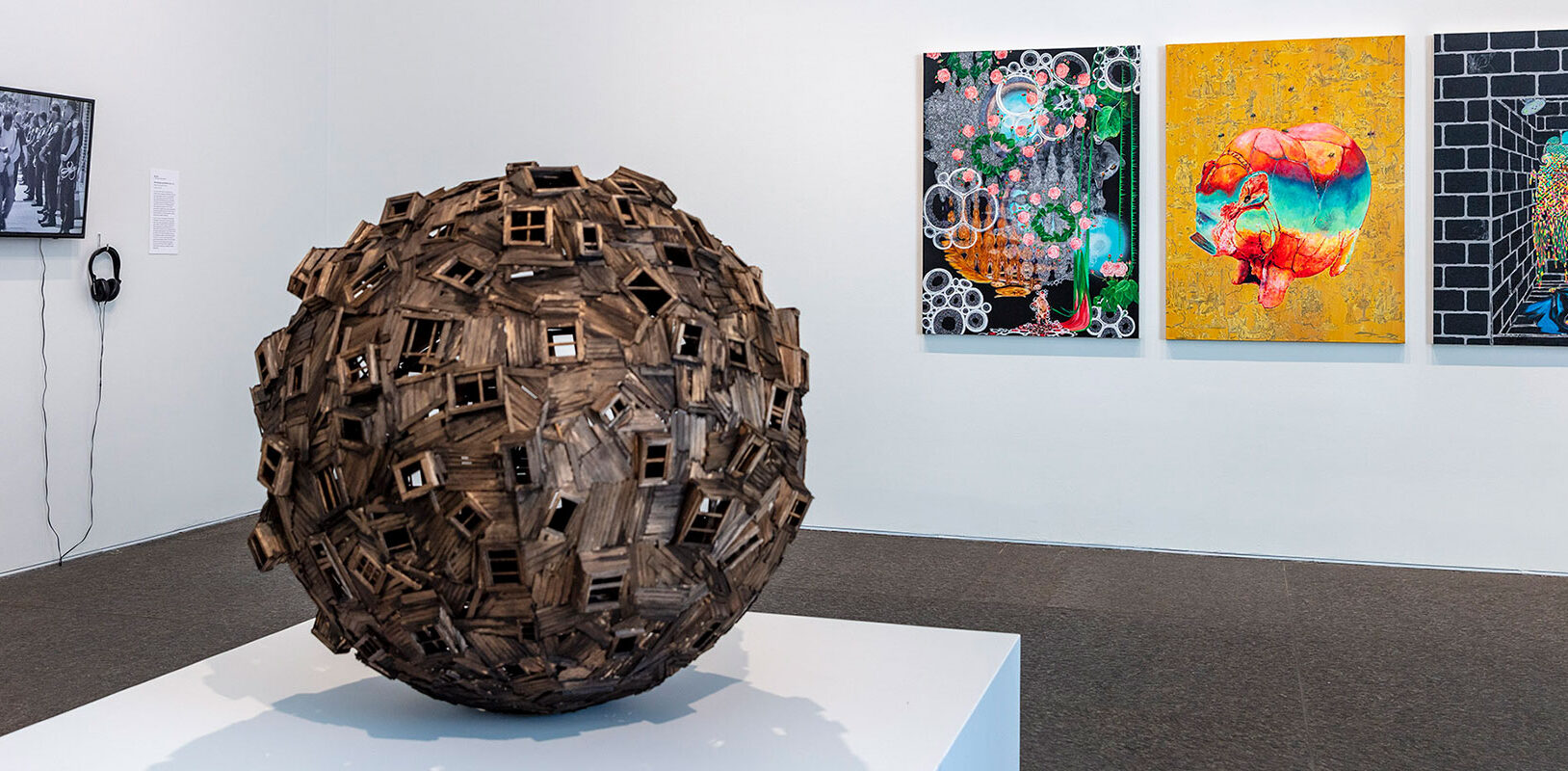 A view of an art gallery with a wooden sphere in the foreground