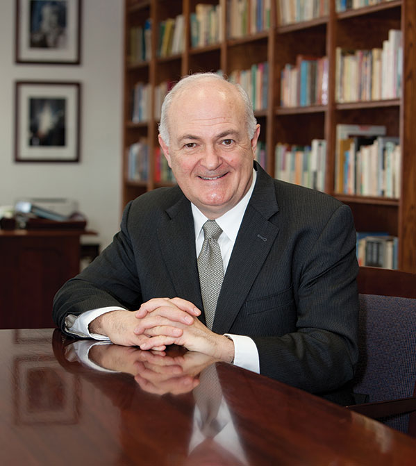 A man sitting at a table with his hands clasped in front of him