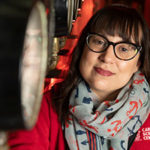 A portrait of a woman with glasses and an anchor patterned scarf