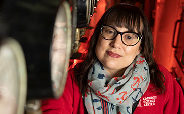 A portrait of a woman with glasses and an anchor patterned scarf