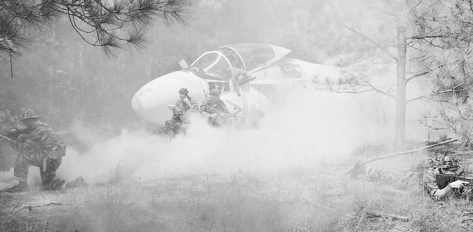 A battle scene of a downed airplane with soldiers nearby