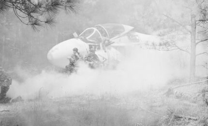 A battle scene of a downed airplane with soldiers nearby