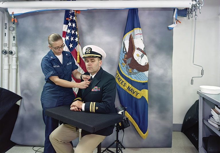 A soldier sitting for a portrait with a a woman adjusting his tie