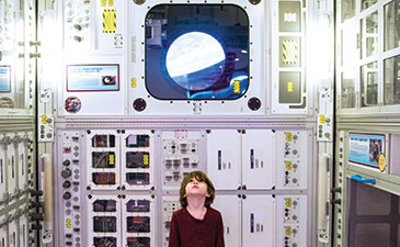 A young boy standing in Carneige Science Center's Space Place, looking up towards the ceiling.