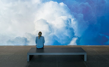 A woman sitting in front of a large photo of clouds