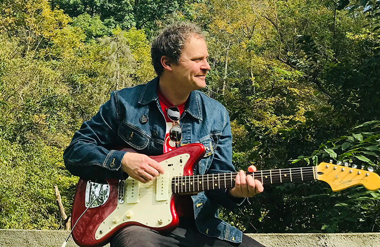 A photo of Ben Harrison holding an electric guitar