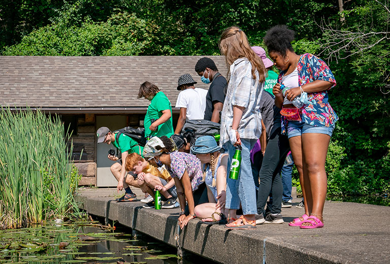 A group of teens looking at a pond