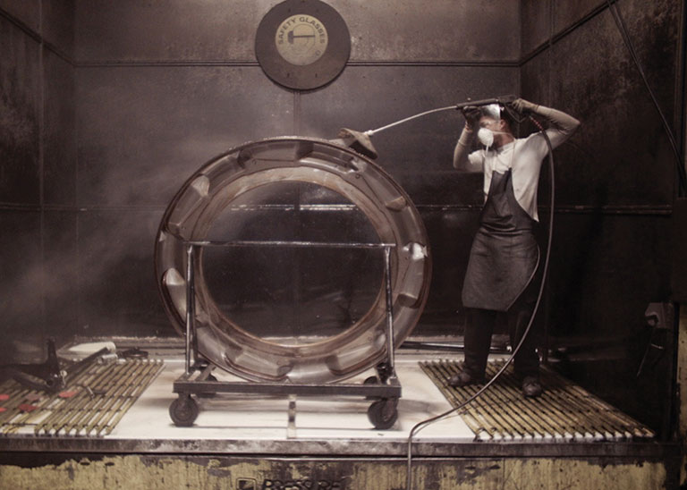 A factory worker hosing off machinery