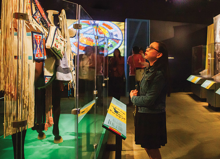 A woman viewing an exhibition of native American clothing