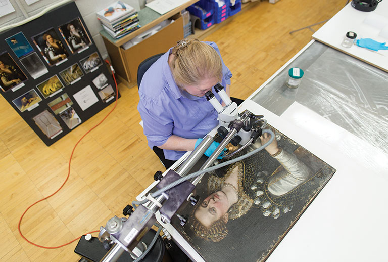 An art conservator at work on a painting