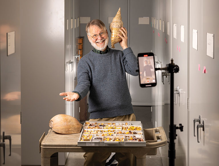 Tim Pearce posing with a alarge shell for a tik-tok video