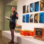 A young curator talking in front of Warhol artwork.