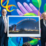 Donors and museum staff standing next to an easel with a large photo of a Science center.