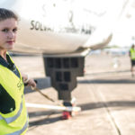 Young female electrical engineer working on teh ground crew of a solar powered plane
