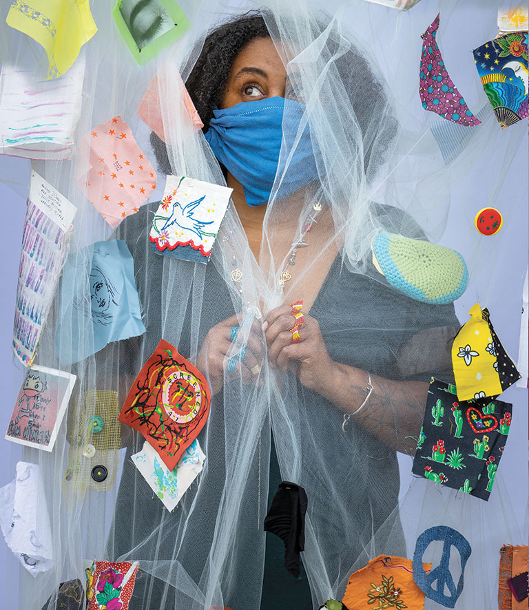 A woman behind a fabric screen with swatches of material around her.
