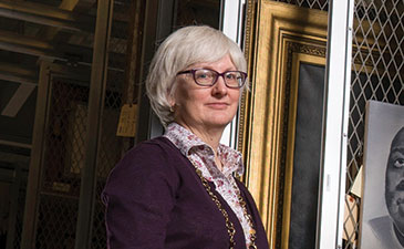 Portrait ohoto fo Elizabeth Tufts Brown standing in art storage area.