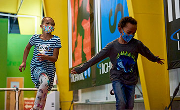 Two young children wearing masks running at carnegie science center sportsworks