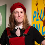 A portrait of Scottie FLora standingin front of artwork at the Warhol Museum
