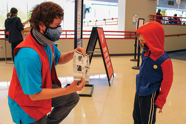 A visitor services member interacting with a child at the Science Center