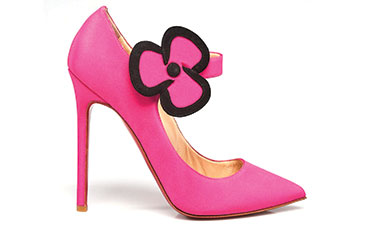 A pink, high-heeled shoe with a large flower shaped buckle