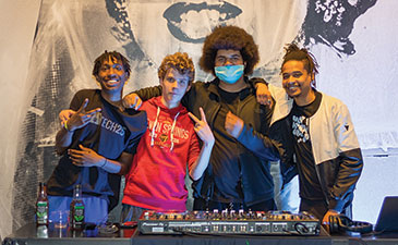 A group of teens posing in front of a turntable.