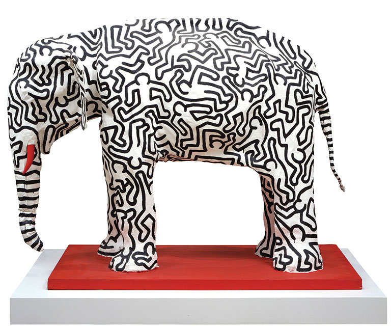 A large plaster elephant with black figures painted on it.