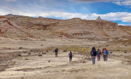 A group walking away from the camera in a large desolate area.