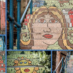 Colorful mosaic staircase featuring abstract faces, landscapes, and patterns, blending art with a public space setting.