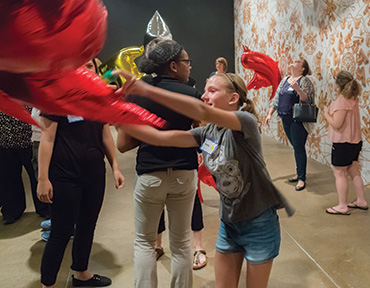 A group of childern and teenagers playing with helium filled balloons.
