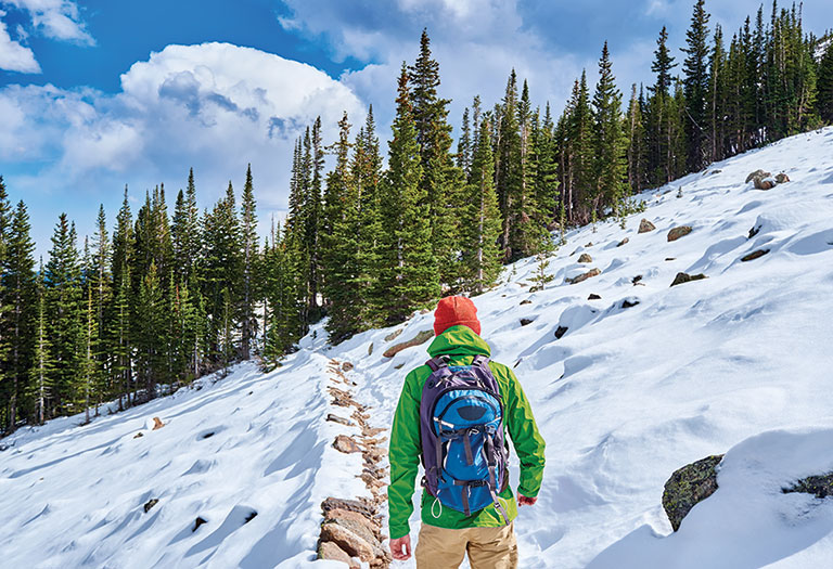 A man walking a long a snowy path.