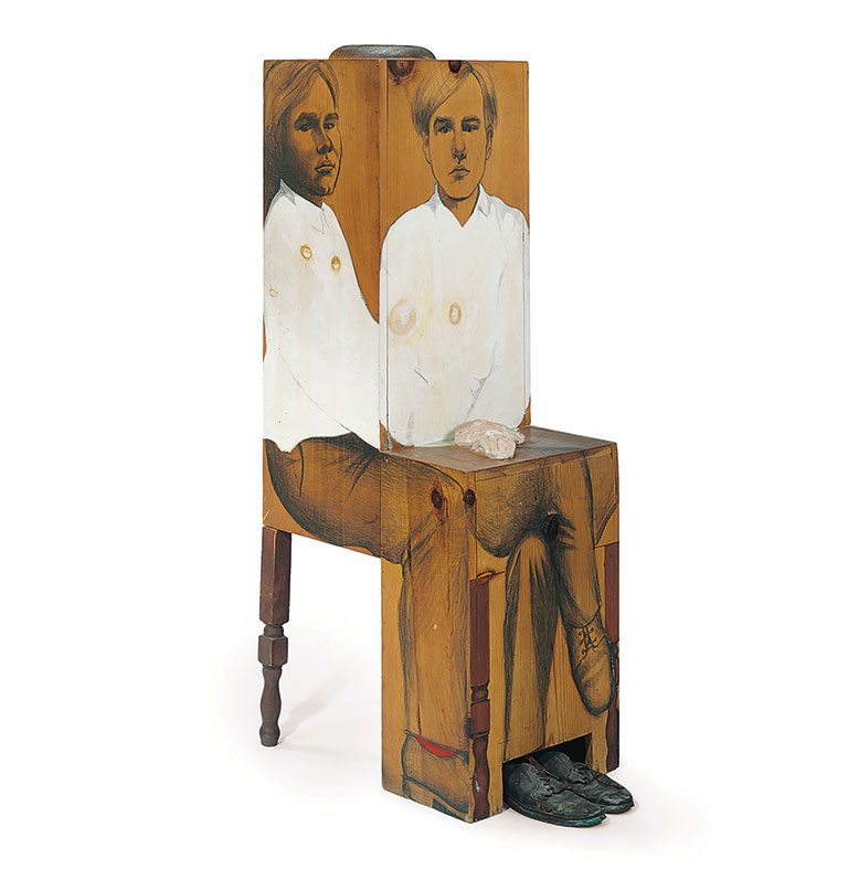 A boxy wooden sculpture of Andy Warhol sitting in a chair