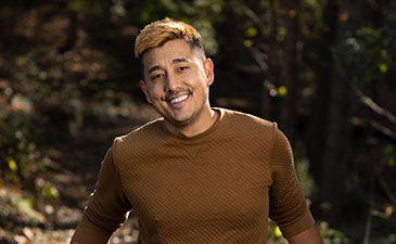 A photo of a young man in a brown shirt smiling