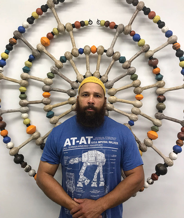 A protrait of Sharif Bey standing in frot of a large necklace