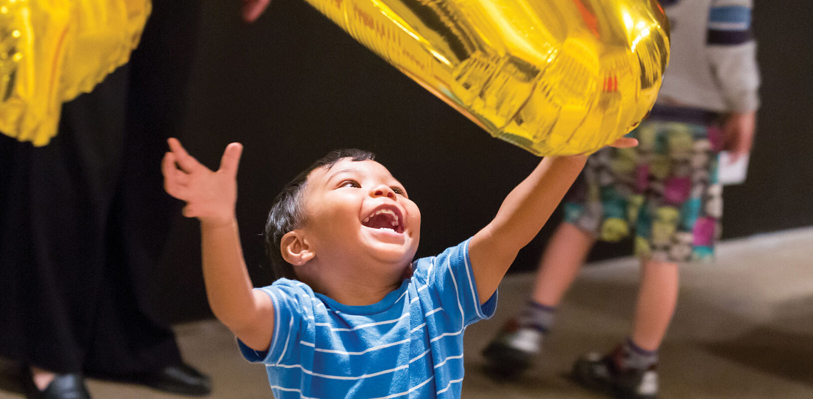 A toddler playing with helium balloons at the Warhol