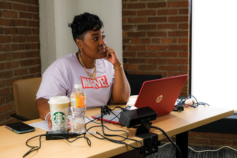 A Black woman in a classroom wearing a Marvel t-shirt