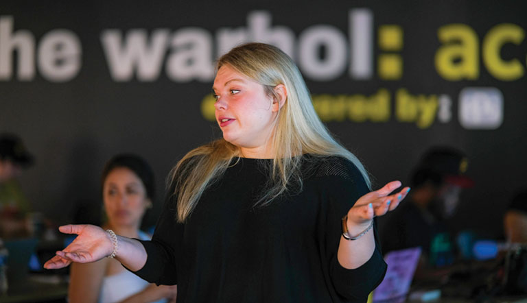 A young female instructor speaking to a class.